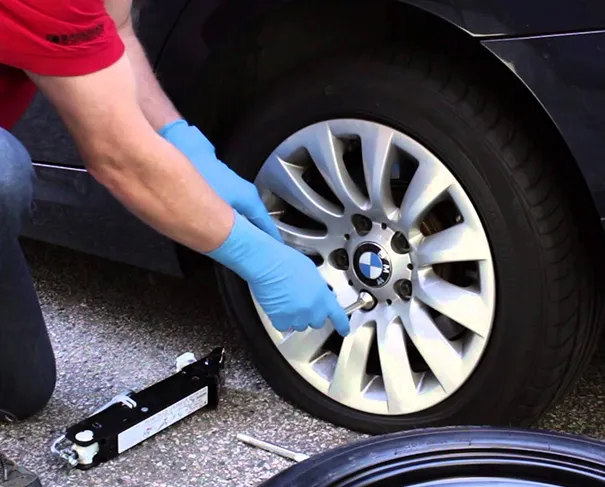 Changing a flat tire on a BMW with a jack.