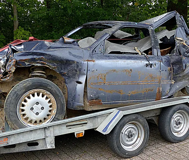Wrecked car on a trailer, ready for junk car removal.