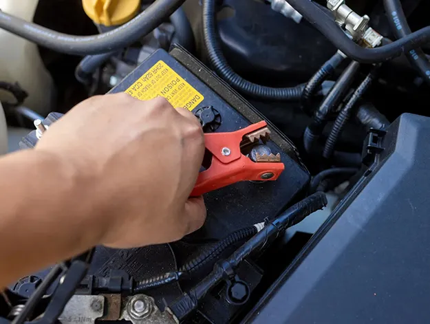 Jump starting a car battery with jumper cables.