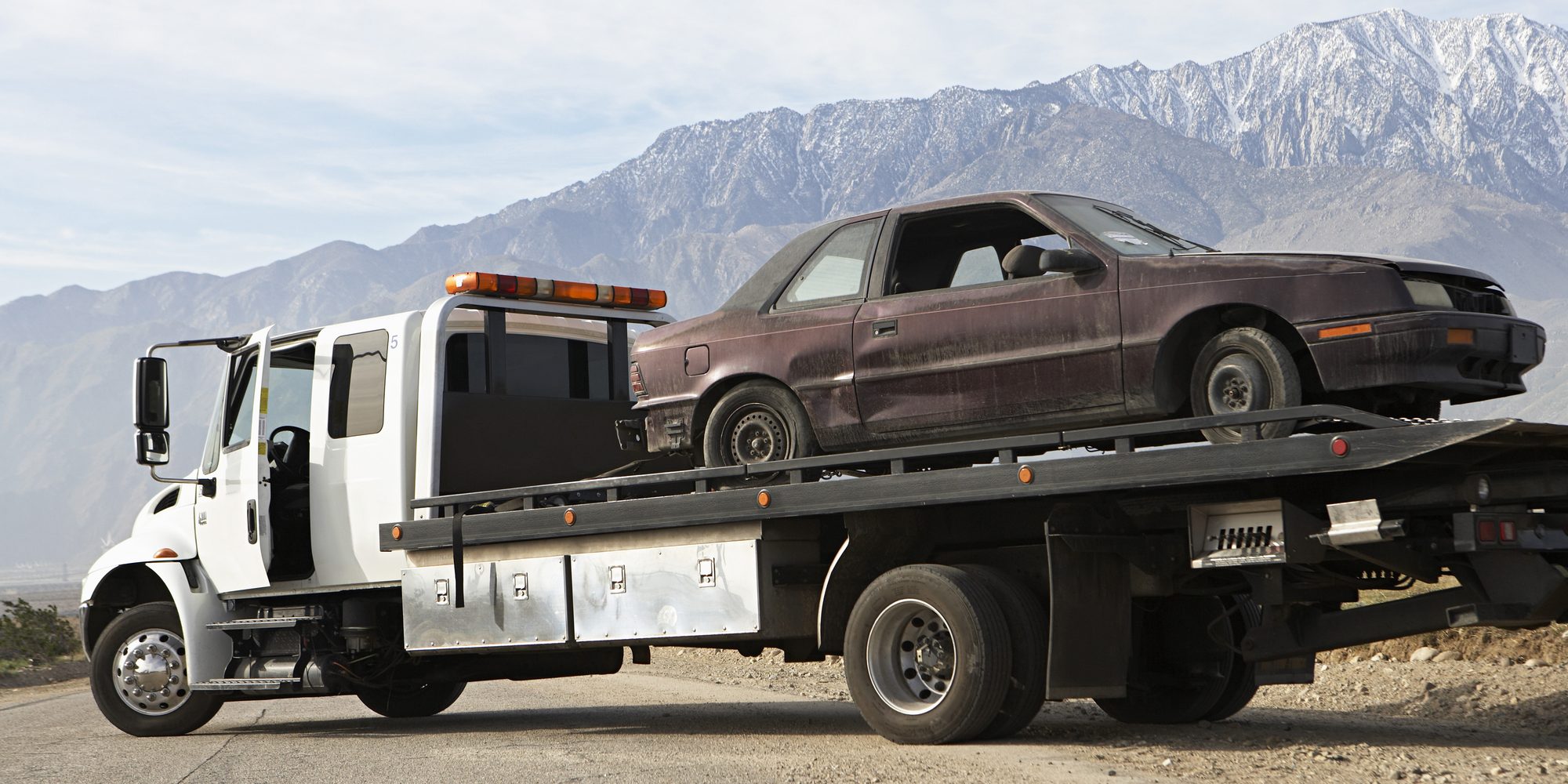 Damaged car on trailer with mountain range in the background